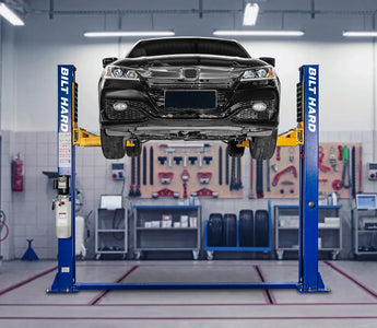 Two-post car lift raising a sedan in garage