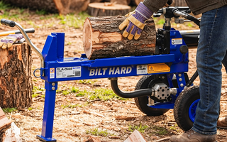 Worker loading a log onto a splitter for fireplace firewood