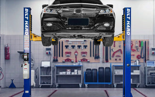 Two-post car lift raising a sedan in garage