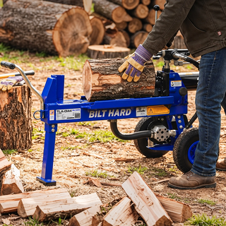 Worker loading a log onto a splitter for fireplace firewood